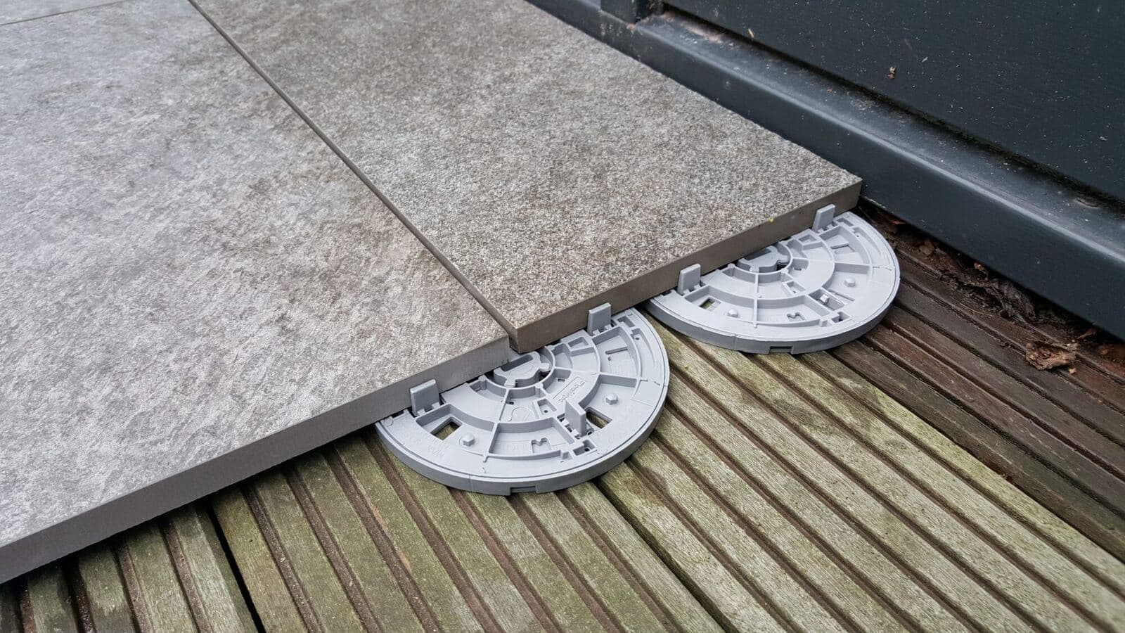 Keramische tegels die los op verstelbare tegeldragers liggen, boven een houten vloer