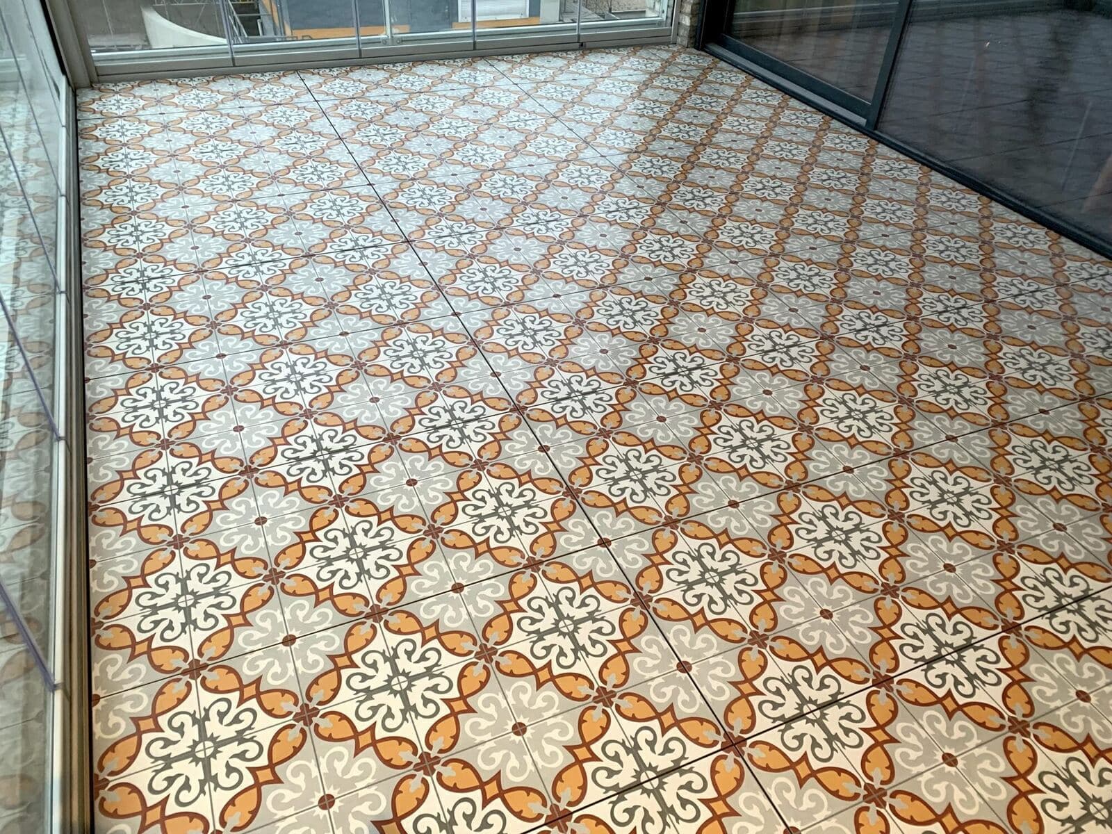 Balkon met gedessineerde decor tegels in oranje, grijs en wit