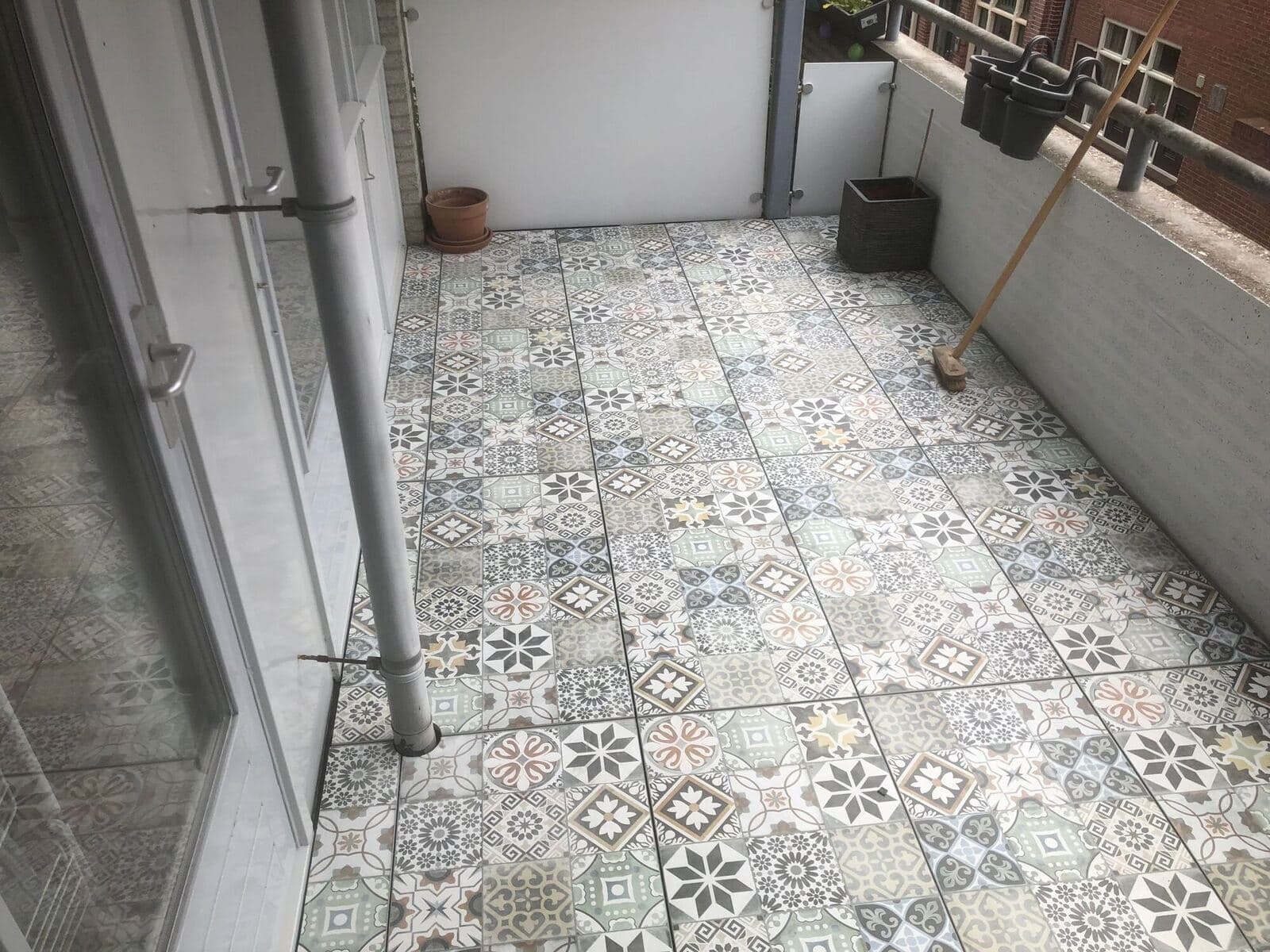Project Leiden Decor tegel: Balkon met decor tegels in een blauwgrijs patroon, langs een wit hekwerk